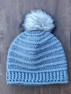 a blue knitted hat with a white pom - pom on the top