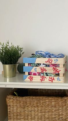 some books are sitting on a shelf next to a potted plant and a wicker basket