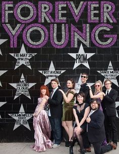 a group of people posing for a photo in front of a wall with the words forever young written on it