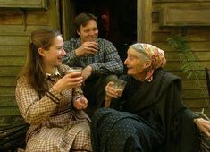 three people are sitting on a bench and one is holding a glass in her hand