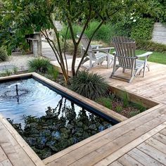 a small pond in the middle of a wooden decked area with chairs around it