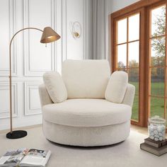 a living room with a large window and a chair next to a lamp on the floor