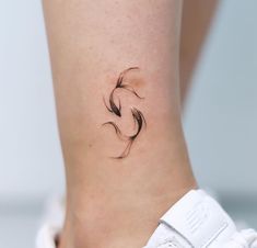 a small tattoo on the ankle of a woman's leg, with black feathers