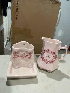 two ceramic dishes sitting on top of a table next to a box with the word bath written on it