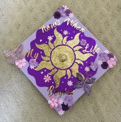 a purple and gold graduation cap with flowers on it