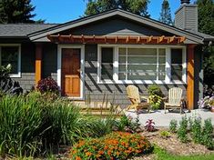 a house with flowers and chairs in the front yard