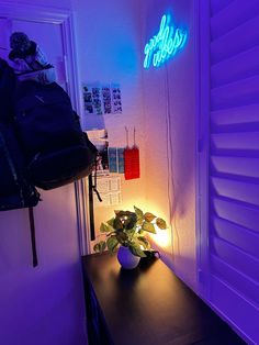 a room with purple lighting and a plant on a table next to the door that is lit up