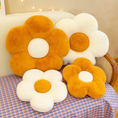 three stuffed flowers sitting on top of a blue and white checkered cloth covered table