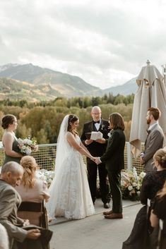 a bride and groom standing at the end of their wedding ceremony with mountains in the background