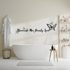 a bath room with a tub and a wall sticker that says, illuminate me beauty sand