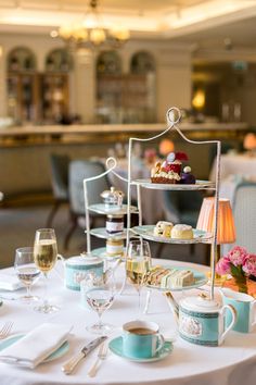 a table topped with plates and cups filled with desserts on top of white cloth covered tables