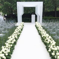 an outdoor ceremony setup with white flowers and clear acrylic chairs in the foreground