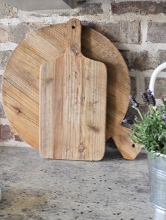 a wooden cutting board sitting on top of a counter next to a potted plant