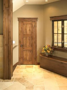 an entry way with a wooden door and window sill on the side, next to a tiled floor