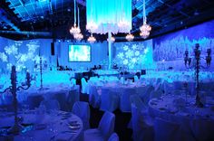 a banquet room set up with white tablecloths, chandeliers and lights