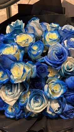 a bouquet of blue and white roses in a black paper wrapper on a table