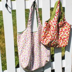 two purses hanging on the side of a white fence