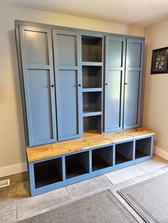 an empty room with some blue cabinets and shelves on the wall, in front of a gray carpeted floor