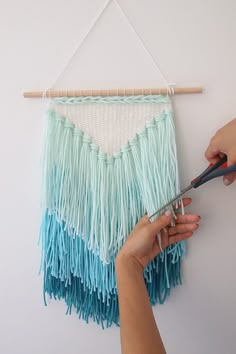 someone is using scissors to make a wall hanging with fringed material on the wall