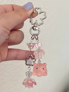 a hand holding a keychain with charms attached to it's sides and an animal charm hanging from the end