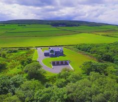 an aerial view of a house in the middle of a lush green field with lots of trees