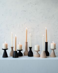 candles are lined up on a table with black and white vases next to each other