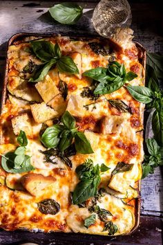 a casserole dish with cheese, spinach and bread toppings on a wooden table