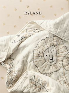 a white quilt with a lion design on it and the words rlyland written in gold