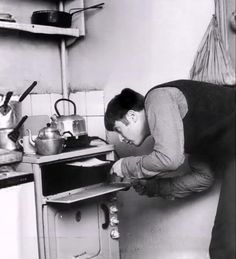 a man bending over to pick something out of the oven while standing in front of it