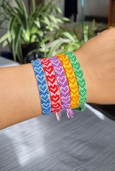 a woman's arm with four different colored bracelets on top of each other