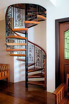 a spiral staircase in a house with stained glass windows and wood flooring on the side