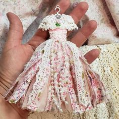 a hand holding a small doll in it's left hand on a lace doily