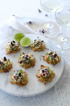 small appetizers are arranged on a white plate with limes and garnishes