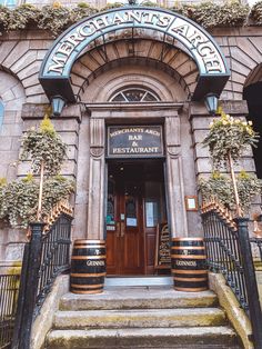 the entrance to an old building with planters and barrels on the steps outside it