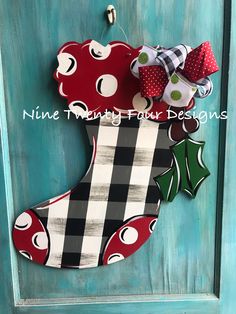 a christmas stocking door hanger made out of wood and fabric with holly decorations on it