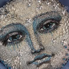 a close up of a person's face made out of silver and blue beads