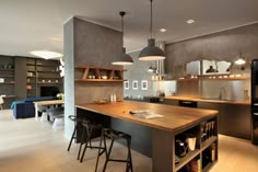 an open kitchen and dining area with bar stools in the center, along with built - in shelving