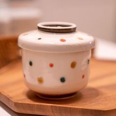 a ceramic container sitting on top of a wooden tray