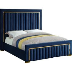 a bed with blue velvet upholstered and gold trimmings on the headboard