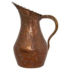 an ornate copper colored pitcher on a white background