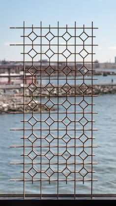 a view of the water and city from behind a metal fence that has been made to look like a grid