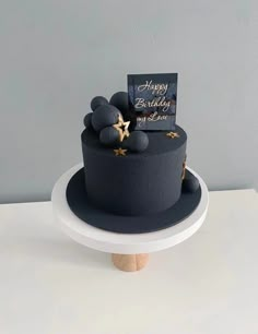 a black and gold birthday cake sitting on top of a white plate with a card