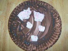 a paper plate with pigs on it sitting on top of a wooden table next to a knife and fork