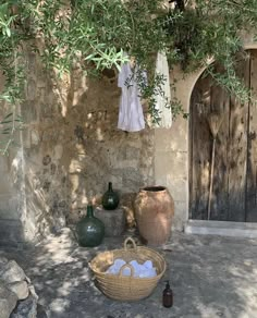 a stone building with an olive tree next to it and some bottles on the ground