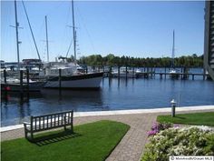 boats are docked in the water next to grass and brick walkways on a sunny day