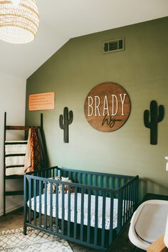 a baby's room with a crib and cactus wall art on the walls