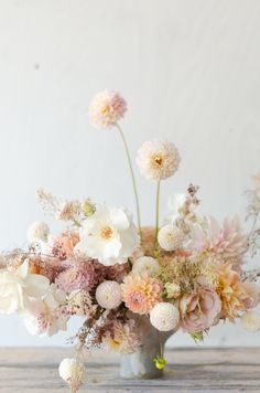 a vase filled with lots of flowers on top of a wooden table