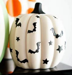 a white pumpkin with black bats painted on it