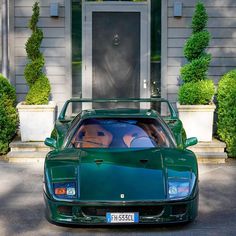 a green sports car parked in front of a house