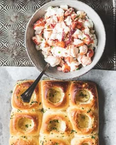 a bowl of crab salad next to a loaf of bread on a table with a spoon